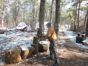 Angelo chopping wood to heat his home(tent)