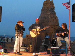 Nick Clemons with Adam Bro and Jim Keegan in a moving musical tribute by the sandcastle in a setting sun